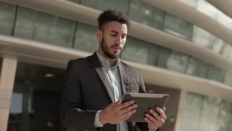 Concentrated-young-businessman-holding-tablet